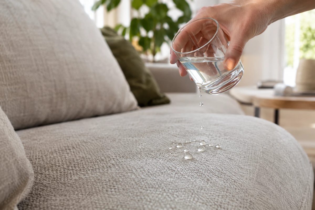 Waterdruppels blijven als bolletjes liggen op de zitting van een geïmpregneerde lichtgrijze stoffen bank