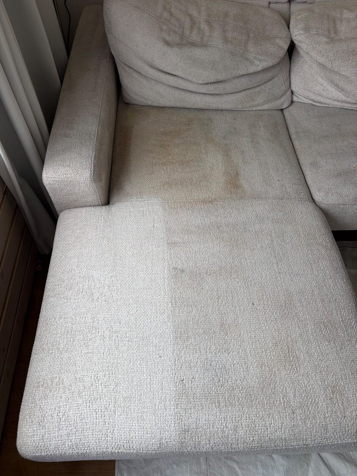 Hoekbank waarvan de chaise longue is gereinigd en de zitting erachter nog zwaar geel verkleurd is